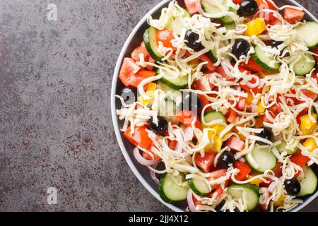 Traditioneller Shopska-Salat mit Gemüse, Oliven und Käse aus nächster Nähe auf einem Teller auf dem Tisch. Horizontale Draufsicht von oben Stockfoto
