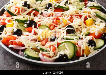 Traditioneller Shopska-Salat mit Gemüse, Oliven und Käse aus nächster Nähe auf einem Teller auf dem Tisch. Horizontal Stockfoto