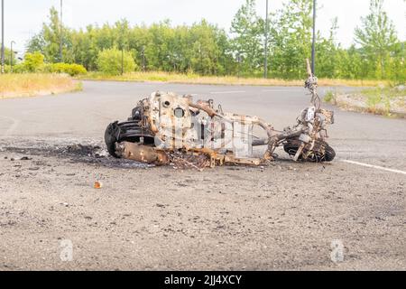 Newburn England: 16.06.2022: Gestohlenes Motorrad, das in Brand gesetzt wurde, brannte aus und wurde auf dem Industriegebiet Road mit grünen Bäumen aufgegeben Stockfoto