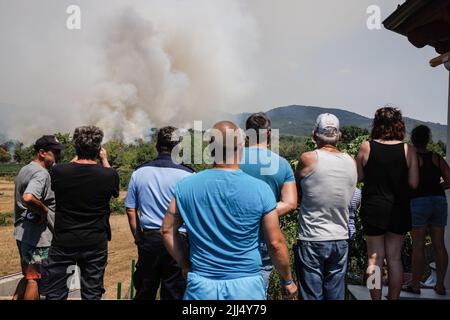 Karst, Slowenien. 22.. Juli 2022. Am sechsten Tag des Feuers beobachten die Menschen ein großes Waldfeuer, das im Wald hinter einem Haus im Dorf Novelo im slowenischen Karst brennt. Etwa tausend Feuerwehrmänner mit Luftunterstützung von drei slowenischen Hubschraubern, zwei serbischen Hubschraubern, einem österreichischen Hubschrauber, einem slowakischen Black Hawk-Hubschrauber und zwei ungarischen Hubschraubern, Ein kroatisches Canadair-Löschflugzeug und ein Pilatus-Flugzeug der slowenischen Armee kämpften weiter gegen ein großes Waldfeuer, das vor fünf Tagen ausbrach und sich in der Karstregion Sloweniens verstärkt hat. Dörfer in der Umgebung w Stockfoto