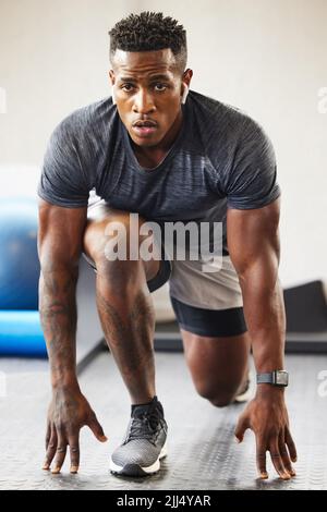 Ich bin bereit, alles zu tun, was es braucht. Ein muskulöser junger Mann trainiert in einem Fitnessstudio. Stockfoto