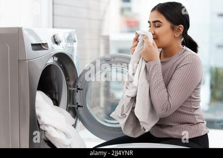 Würden Sie eine Nase voll davon bekommen? Eine schöne junge Frau, die die Wäsche zu Hause macht. Stockfoto