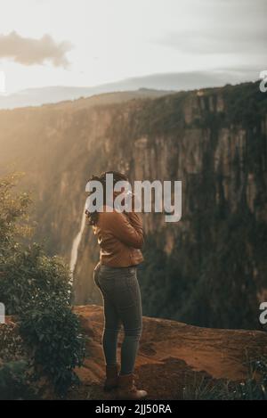 Junge Frau Tourist mit Vintage Retro-Kamera. Junge modische Reisende, die bei Sonnenuntergang Fotos in der Natur machen Stockfoto