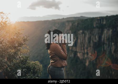Junge Frau Tourist mit Vintage Retro-Kamera. Junge modische Reisende, die bei Sonnenuntergang Fotos in der Natur machen Stockfoto