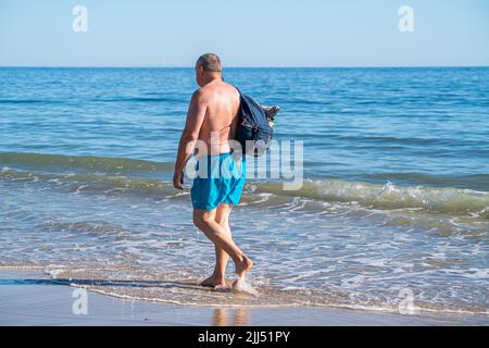 23. Juli 2022: Rückansicht eines Mannes, der mit einem Rucksack an der Küste des Ozeans läuft Stockfoto