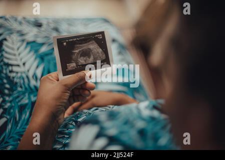 Eine schwangere Frau, die drinnen ein Sonogramm hält Stockfoto