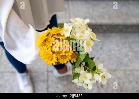 Junge Frau mit Blumenstrauß auf den Feldern. Stockfoto