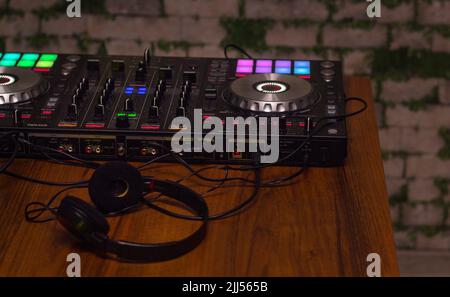 DJ-Mixer-Controller-Panel zum Spielen von Musik und Feiern. DJ-Mixer und Kopfhörer auf dem Tisch Stockfoto