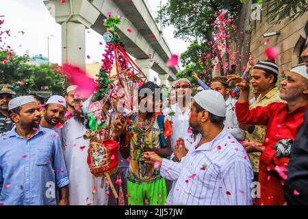 Neu-Delhi, Indien. 22.. Juli 2022. Menschen, die der muslimischen Gemeinschaft angehören, duschen Blütenblätter auf Kanwariyas, Anhänger der Hindu-Gottheit Shiva, während sie während der Kanwar Yatra im Monat Shravan in Neu-Delhi heiliges Wasser aus dem Ganga-Fluss transportieren. Die Kanwar Yatra ist eine jährliche Pilgerfahrt, bei der die Anhänger safranfarbene Kleidung tragen und barfuß laufen, um das heilige Wasser von den ausgewählten Pilgerzielen zu sammeln. Kredit: SOPA Images Limited/Alamy Live Nachrichten Stockfoto