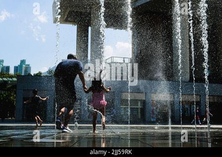 Hongkong, China. 23.. Juli 2022. Kinder spielen während einer Hitzewelle vor dem Springbrunnen. Heute markiert Da Shu, oder die "große Hitze", die 12. der 24 Sonnentermine im traditionellen chinesischen Kalender, auch die heißeste Temperatur, die jemals bei 34 gemessen wurde. Kredit: ZUMA Press, Inc./Alamy Live Nachrichten Stockfoto