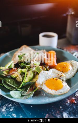 Frisches Frühstück mit Spiegeleiern, Brot, Avocado, rotem Fischlachs und Kaffee Stockfoto