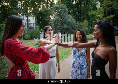 Eine Gruppe von Mädchen verschiedener Ethnien verbindet Hände und Lächeln, Freundschaft und Integration zwischen verschiedenen Frauen Stockfoto