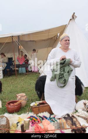 Nachstellung eines Wikingerbauers, der ein Kleidungsstück von Hand näht. Upholland Green fayre, Lancashire, England 23-07-2022 Stockfoto