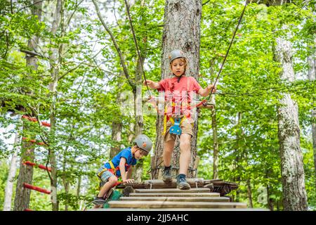 Glückliches Kind im Helm, gesunder Teenager Schuljunge, der an einem Sommertag in einem Kletterabenteuer-Park aktiv ist Porträt eines verärgerten Mädchens Stockfoto