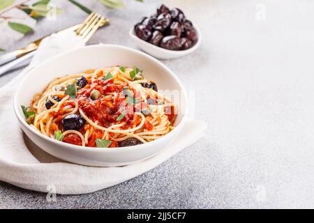 Spaghetti alla puttanesca . Italienische Pasta mit Tomaten, Oliven, Kapern, Sardellen und Petersilie. Italienisches Essen. Speicherplatz kopieren Stockfoto