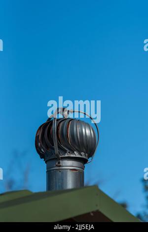 Gemeinsamer Abluftventilator für Turbinen auf einem Badezimmerdach mit blauem Himmel Stockfoto