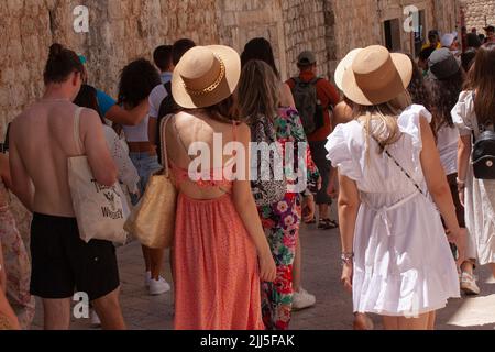 Zwei junge Mädchen in Sommerkleidung, die von hinten gesehen werden, schlendern mit anderen Touristen in einem alten südeuropäischen Viertel. Dubrovnik, Kroatien - Juli 13, Stockfoto