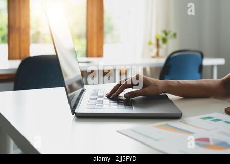 Nahaufnahme der weiblichen Hände, die im Büro einen Laptop benutzen, die Hände der Frau, die im Innenraum auf der Laptop-Tastatur tippen, Seitenansicht der Geschäftsfrau, die den Computer benutzt Stockfoto
