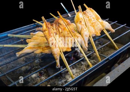 Stempelschnitt von Chicken Wings Spiessen auf dem Herd, auf schwarz isoliert. Stockfoto