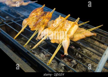 Stempelschnitt von Chicken Wings Spiessen auf dem Herd, auf schwarz isoliert. Stockfoto