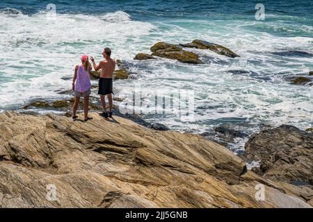 Paar stehen auf den Felsen am Meeresrand im Beaver Tail State Park, Jamestown, Rhode Island Stockfoto