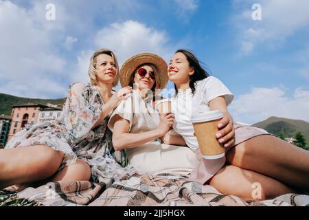 Multirassische Freunde mit Einweg-Kaffeetassen genießen sonnigen Tag Stockfoto