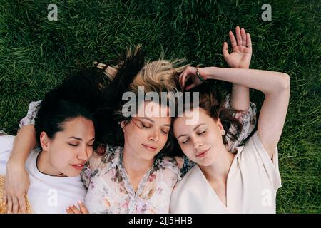 Freunde mit geschlossenen Augen liegen auf Gras im Park Stockfoto