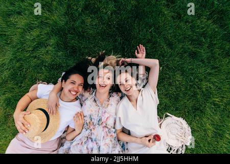 Fröhliche Frauen, die Spaß haben, im Park zu liegen Stockfoto