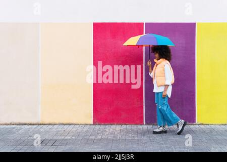 Mädchen zu Fuß mit bunten Regenschirm Stockfoto