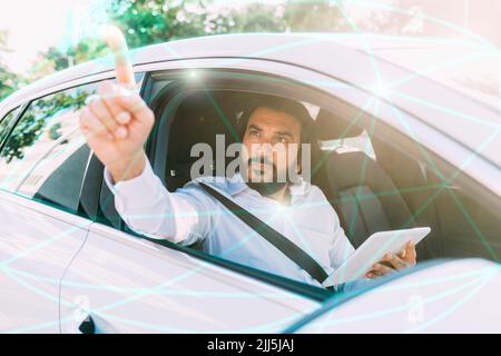 Reifer Mann mit Tablet-PC auf virtuellen Bildschirm sitzen im Auto Stockfoto