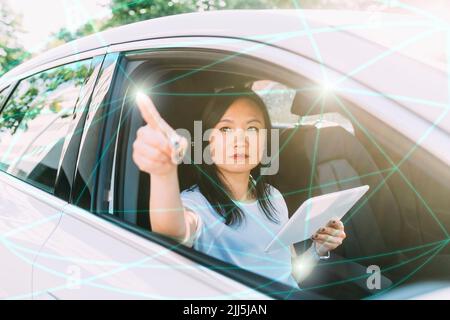 Geschäftsfrau mit Tablet-PC, der Linien und Punkte auf dem virtuellen Bildschirm im Auto verbindet Stockfoto