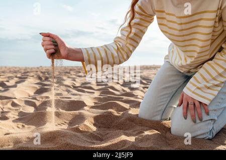 Sand, der aus der Hand einer Frau am Strand ausläuft Stockfoto