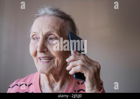 Glückliche ältere Frau, die auf dem Smartphone spricht Stockfoto