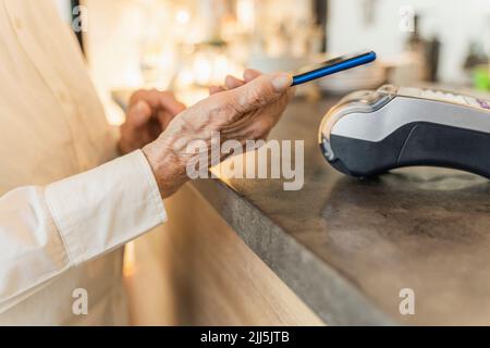 Ältere Frau, die per Smartphone bezahlt Stockfoto