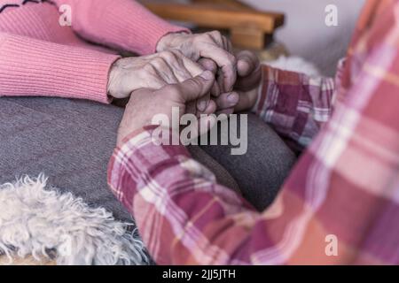 Mann, der die Hände einer älteren Frau zu Hause hält Stockfoto