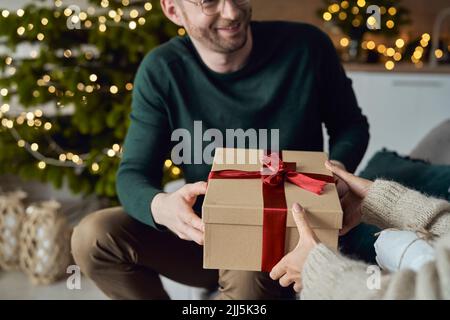 Lächelnder Mann, der der Frau zu Hause ein Geschenk macht Stockfoto