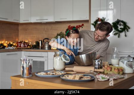 Happy girl Mischen Cookie Teig stehen von Vater in der Küche Stockfoto