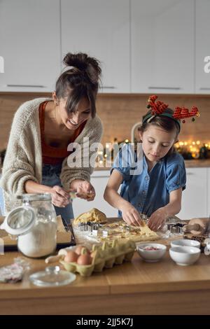 Lächelnde Mutter mit Tochter, die in der Küche Kekse machte Stockfoto