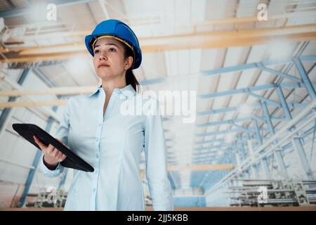 Junge Ingenieurin mit Hardhat und Tablet-PC im Werk Stockfoto