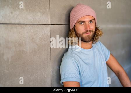 Selbstbewusster Mann mit Strickmütze an der Wand Stockfoto