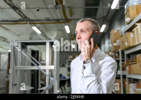 Geschäftsmann, der in der Fabrik auf dem Smartphone spricht Stockfoto