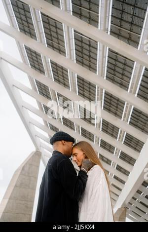 Junger Mann küsst Frau auf der Stirn unter dem Dach stehend Stockfoto