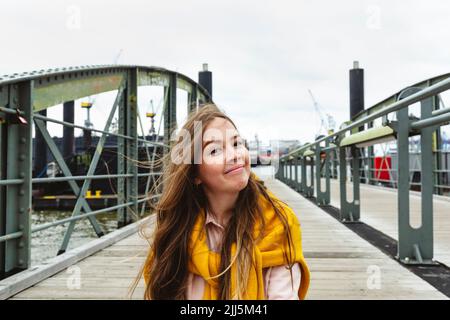 Lächelnde Frau mit braunen Haaren sitzt auf dem Steg Stockfoto