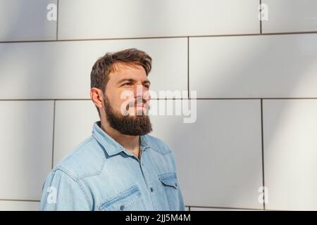 Lächelnder bärtiger Mann, der vor der Wand steht Stockfoto