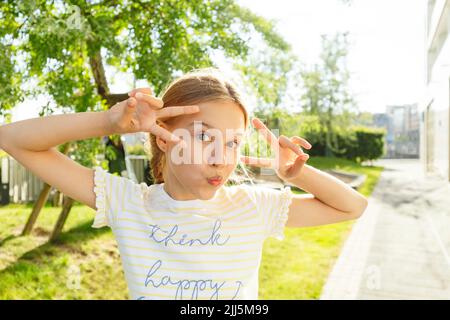 Mädchen mit Friedensschild vor dem Baum Stockfoto