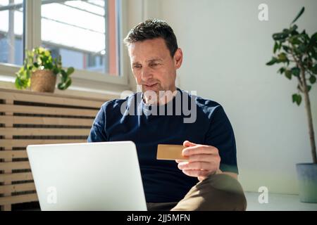 Ein Geschäftsmann, der im Büro Online-Banking über einen Laptop macht Stockfoto