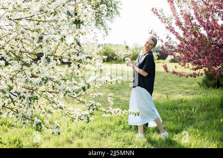 Glückliche Frau mit weißen Blumen im Garten Stockfoto