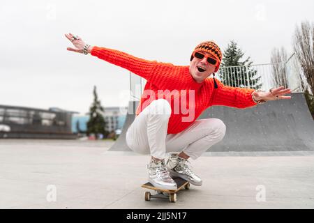 Glücklicher reifer Mann mit ausgestreckten Armen genießt auf dem Skateboard Stockfoto