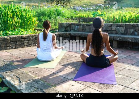 Mädchen mit Yogalehrer meditiert im Park Stockfoto