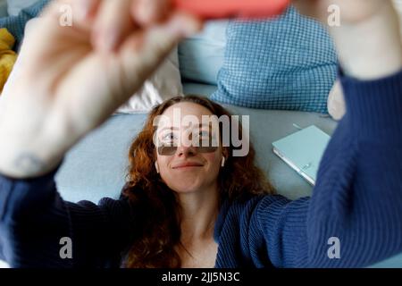 Frau trägt unter Augenflecken und nimmt zu Hause Selfie auf Stockfoto